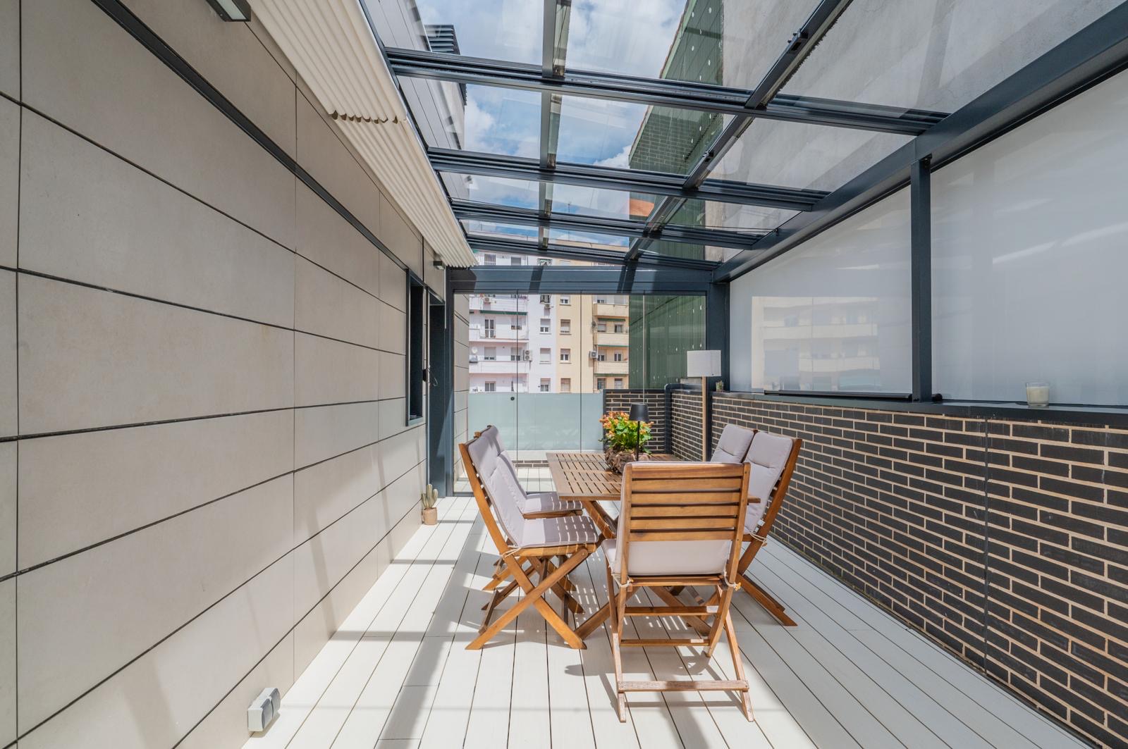Terraza acristalada con mesa de madera